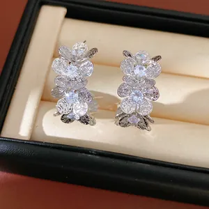 Macro view of C-shaped earrings featuring wrinkled flowers and sparkling zircons.