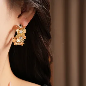 Detailed macro shot of elegant gold floral C-shaped earrings with sparkling zircons