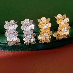 Close-up detail of silver needle flower C-shape earrings with zircon inlay in gold and silver