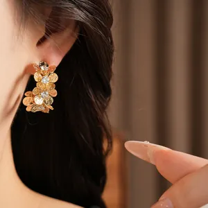 Detailed view of gold wrinkled flower C-shaped earrings with sparkling cubic zirconia