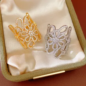 Detail view of shimmering zircon pave hollow flower open rings in gold and silver
