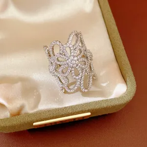 Close-up of intricate hollow flower ring with pavé-set zircons in jewelry box.