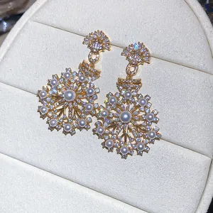 Close-up of vintage snowflake earrings with sparkling zircons and elegant white pearls