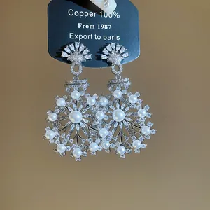 Detailed view of elegant silver zircon snowflake earrings with white pearls in vintage style.