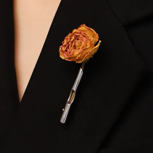 Silberne Vasen-Brosche aus Metall mit kleiner orangefarbener Rose auf schwarzem Revers