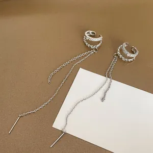 Close-up detail of silver double-layered ear cuff with sparkling zircon and long chain.