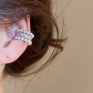 Detailed macro view of an elegant pearl and zircon non-pierced ear cuff on a model