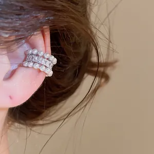 Close-up detail of an elegant three-row zircon and pearl ear cuff on a model's ear