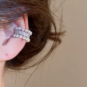 Close-up of elegant zircon and pearl ear cuff worn on the ear bone