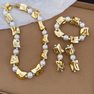 Elegant jewelry set with irregular gold metal and white pearls on brown background
