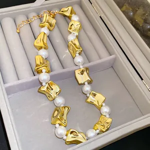 Close-up of elegant irregular gold metal and pearl necklace in grey jewelry box