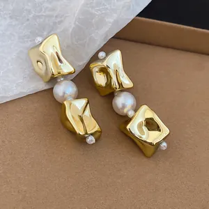 Detailed close-up showing textured irregular gold earrings with elegant pearl accents
