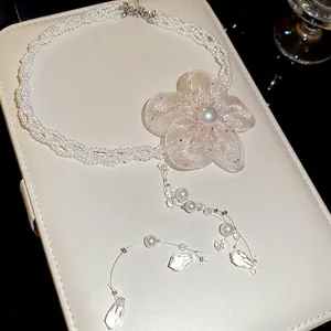 Close-up of elegant pearl necklace with light pink chiffon flower and crystal pendants