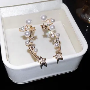 Boucles d'oreilles élégantes avec étoiles, perles et zircons dans un écrin blanc.
