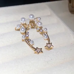 Élégantes boucles d'oreilles étoile et perle dorées avec zircons sur plateau velours