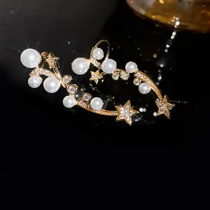 Détail de boucles d'oreilles grimpantes élégantes en perles et étoiles avec zircons.