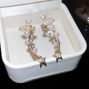 Vue détaillée de boucles d'oreilles étoiles et perles avec zircons dans un coffret