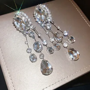 Sparkling oversized rhinestone oval and teardrop tassel clip-on earrings displayed on gift box