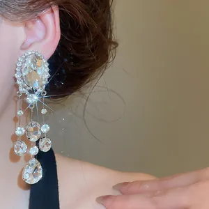 Close-up of elegant rhinestone tassel earrings with oval and teardrop crystals.