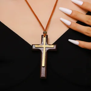 Detail of wooden cross necklace with metallic gold layer on a dark suede leather cord