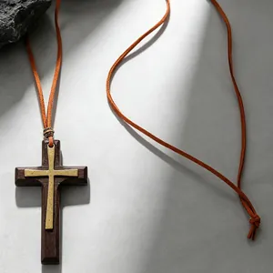 Macro detail of gothic wooden cross pendant with gold metal inlay on suede cord