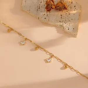 Detail view of a 18K gold butterfly anklet with small gold beads on a steel chain
