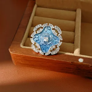 Close-up of vintage blue enamel flower ring with sparkling rhinestones on a wooden box.