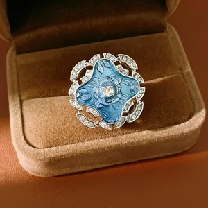 Close-up of a blue enamel flower ring with sparkling rhinestones in a brown velvet box
