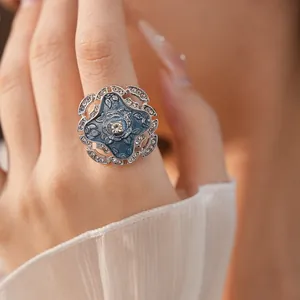 Close-up view of a vintage blue enamel flower ring with shimmering crystal pavé details