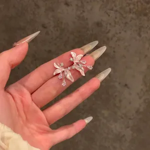 Dettaglio di eleganti orecchini a fiore di iris rosa con zirconi lucenti sulla mano