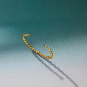 Detailed view of a gold-plated twisted stainless steel cuff with green stones.