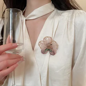 Detail view of a vintage pink crystal beaded flower brooch on a beige blouse