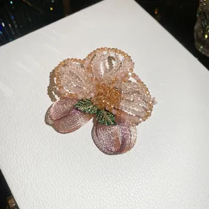 Close-up of vintage crystal beaded floral brooch with intricate embroidery details.