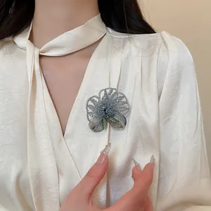 Detailed shot of a vintage crystal beaded and embroidered flower brooch on a white blouse.