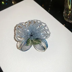 Detailed macro view of a vintage handcrafted light blue crystal beaded flower petal brooch