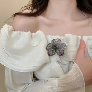 Close-up of retro crystal beaded flower brooch on elegant white pleated dress garment.