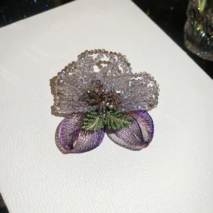 Detailed view of the handcrafted crystal beaded flower brooch with purple mesh petals.