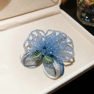 Detailed close-up of a vintage blue crystal beaded brooch with wire embroidery leaves