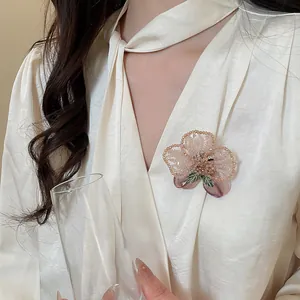 Detailed view of a vintage crystal beaded flower brooch on a white satin blouse