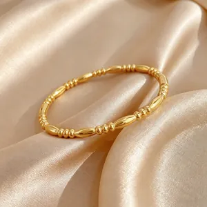 Close-up detail of minimalist gold-plated titanium steel beaded zen staff bangle