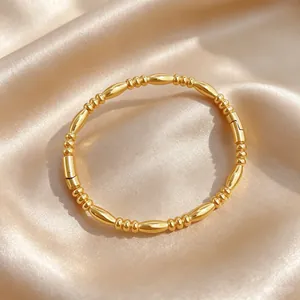 Close-up detail of a minimalist gold-plated titanium steel bangle with bamboo bead design.