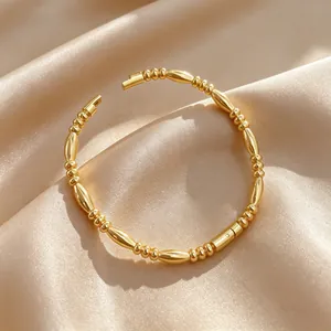 Close-up of minimalist gold titanium steel beaded cuff bracelet on silk background