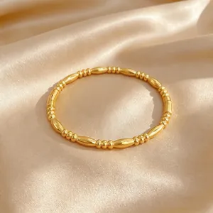 Close-up of minimalist gold-plated titanium steel beaded bangle on silk background