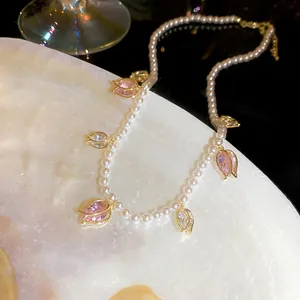 Gros plan d'un collier de perles vintage français avec des pendentifs tulipes roses