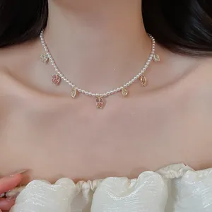 Gros plan détaillé montrant les élégants pendentifs tulipes et perles blanches du collier.
