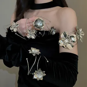 Detail shot of silver metallic flower arm cuff jewelry worn on black velvet dress