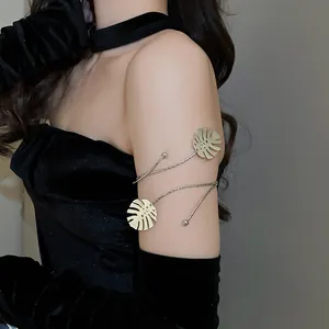Detailed close-up of a gold metal monstera leaf arm cuff worn on a model's upper arm