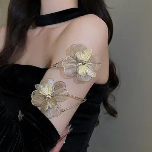 Detailed view of an elegant metallic gold floral arm cuff worn on a black velvet sleeve
