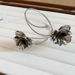 Detailed close-up of a silver-toned metal arm cuff featuring intricate floral details.