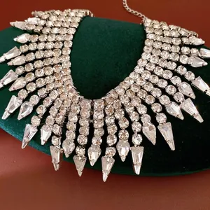 Elegant statement rhinestone tassel necklace with teardrop crystals on green velvet display